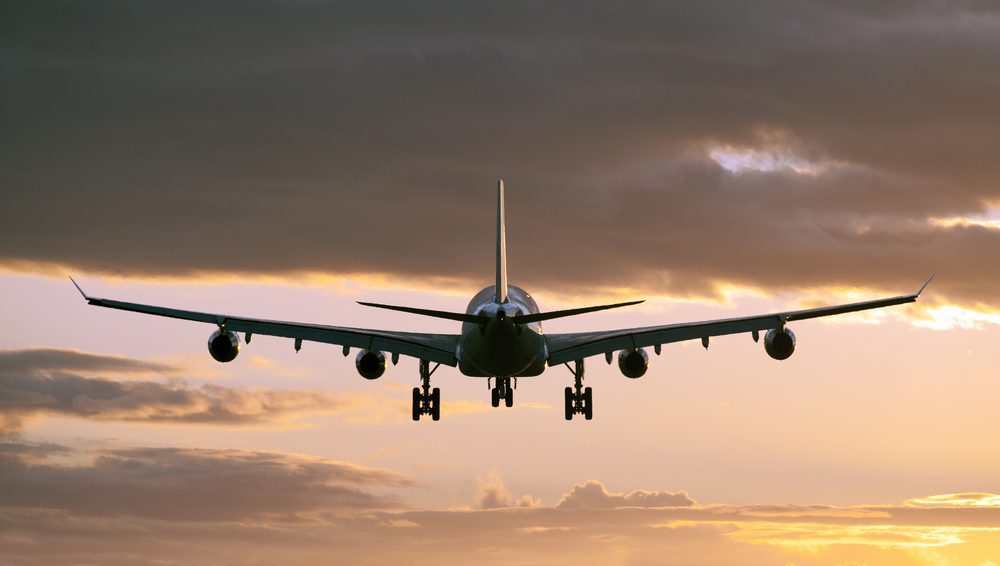 Un gros avion-cargo survolant la ville au coucher du soleil, illustrant la rapidité et l'ampleur du transport aérien de marchandises entre la Chine et l'Europe.
