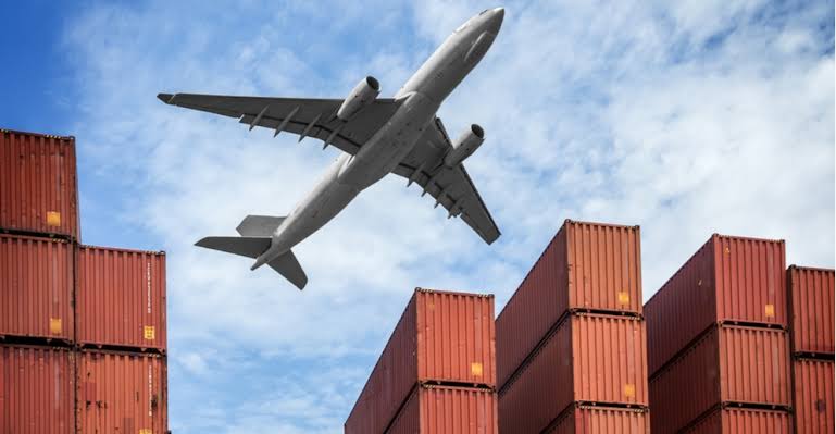 Un avion-cargo survolant des conteneurs empilés sur fond de ciel bleu, symbolisant les services de fret aérien DDP entre la Chine et les États-Unis.
